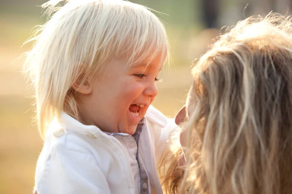 Blonde maman avec garçon fils jouer dans un parc — Photo