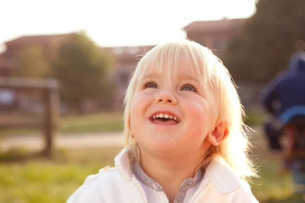 Loira caucasiano menino sorri ao ar livre no parque — Fotografia de Stock