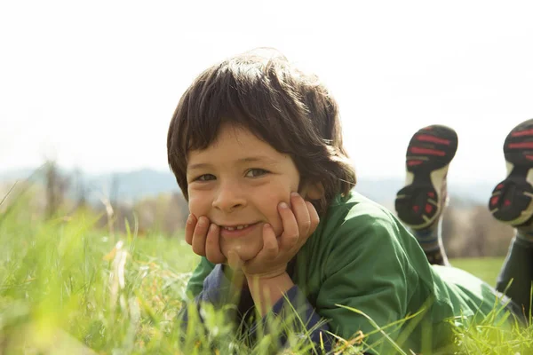 Lächelnder Junge liegt draußen im Gras — Stockfoto