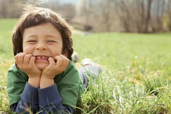 Lachende jongen jongen liggen buiten in het gras — Stockfoto