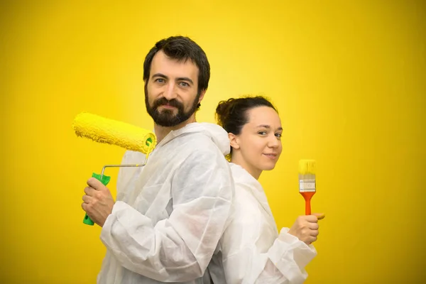 Άνδρας και γυναίκα ζευγάρι με κίτρινο πινέλο και ρολό έτοιμα να διακοσμήσουν το σπίτι — Φωτογραφία Αρχείου