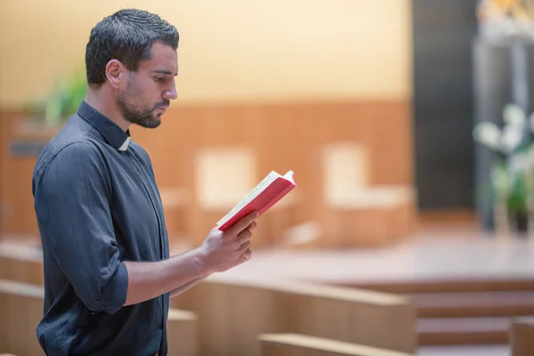 Jovem barba homem vestindo camisa azul orando com a bíblia na igreja moderna — Fotografia de Stock