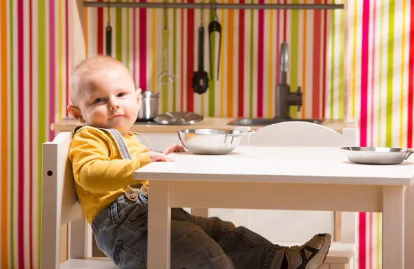 Семейный мальчик сидит на игрушечной кухне — стоковое фото