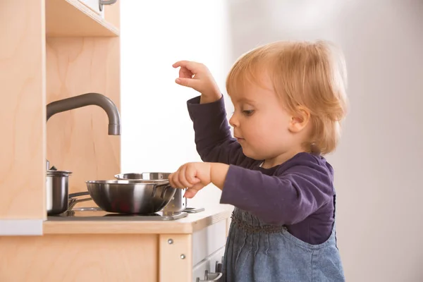 Дочь играет в приготовление пищи на игрушечной кухне — стоковое фото