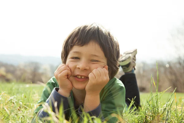 Lächelnder Junge liegt draußen im Gras — Stockfoto