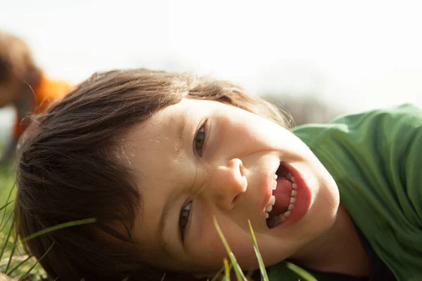 Sonriente chico mentira al aire libre en la hierba — Foto de Stock