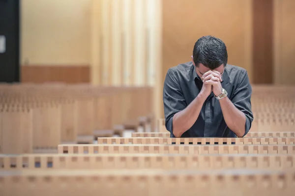 Молодий бородатий чоловік у блакитній сорочці молиться в сучасній церкві — стокове фото