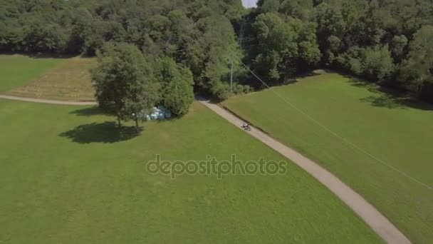 Nő anya MTB gyerekekkel pótkocsi útra kültéri, természet, le egy oldalsó séta, napos 4k légi drone kövesse széles lövés — Stock videók