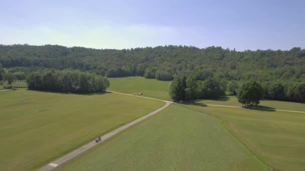 Femme maman VTT avec enfants remorque balade en plein air dans la nature en bas d'une promenade latérale dans la journée ensoleillée 4k drone aérien suivre plan large — Video