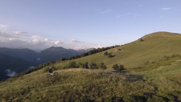 Motorcu iz sürmek offroad yolu üzerindeki ahşap orman valley yakınındaki dağ bisikleti tarafından yaz güneşli gün, yaklaşan günbatımı veya gündoğumu şafak veya robot alacakaranlık 4 k hava izleyin uçuş geniş vurdu — Stok video