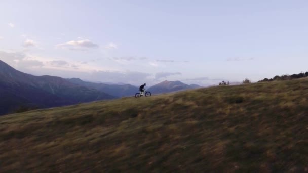Biker trail ritje op offroad pad met de mountainbike in zonnige zomerdag, naderende zonsondergang of zonsopgang dawn of schemering 4k luchtfoto drone Volg vlucht breed schot — Stockvideo