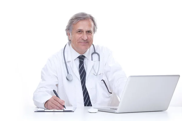 Szczęśliwa starszym lekarzem z stetoskop pracę z laptopa na białym tle — Zdjęcie stockowe