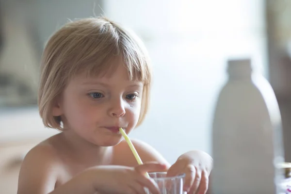 Candid baby girl having breakfast drinking milk at home in summer day — Stock Photo, Image