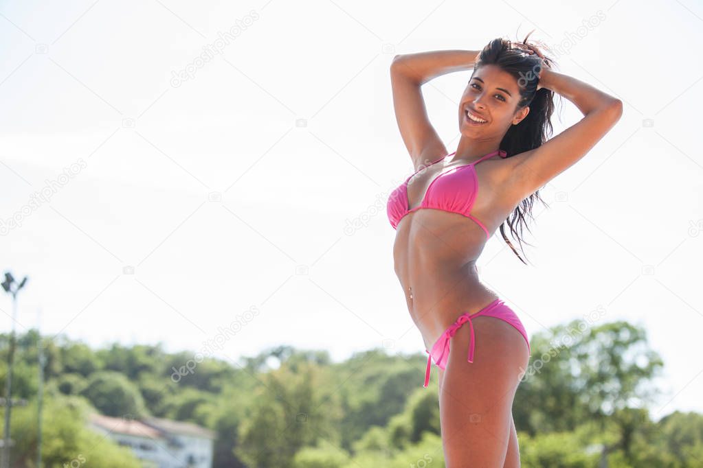 beautiful young latina woman in pink bikini portrait at swimming pool