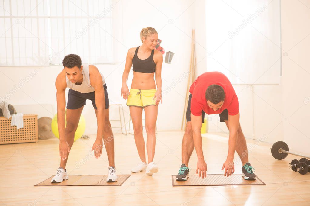 Group of young people do stretching exercise in gym