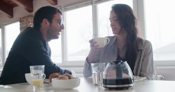 Joven pareja caucásica en el amor hablando mientras toma el desayuno italiano y café americano interior en moderno industrial house.4k toma de vídeo portátil — Vídeos de Stock