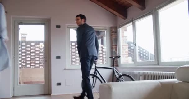 Hombre apurado tomar bicicleta para ir a trabajar besando a su novia interior en la casa industrial moderna. 4k toma de vídeo portátil — Vídeo de stock