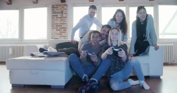 Többnemzetiségű csoport meg emberek pihentető a kanapén játszik a videojátékok és a szórakozás fedett modern ipari házban. 4 k kézi videóval — Stock videók