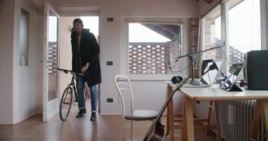 siyah adam yaratıcı müzisyen bisikletle ev kayıt stüdyosuna geri dönecek ve modern endüstriyel evde kapalı işe almak. 4 k el video çekim