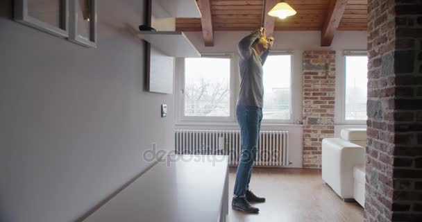 Joven hombre negro relajante escuchando música con auriculares para teléfonos inteligentes y bailando en interiores en la casa industrial moderna. 4k toma de video en cámara lenta de mano — Vídeo de stock