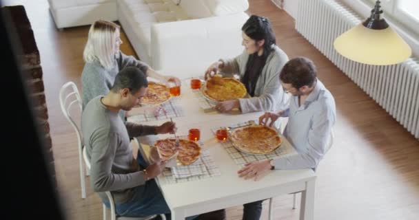 Multi-etnische groep vrienden mensen genieten van lunch of diner maaltijd samen eten pizza binnen in industriële stadsvilla. 4 k handbediende slowmotion bovenaanzicht overhead video schot — Stockvideo