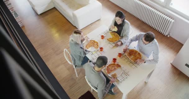 Çok ırklı bir grup arkadaş insan zevk birlikte pizza kapalı modern endüstriyel evde yemek öğle veya akşam yemeği yemek. 4 k el yavaş hareket üstten görünüm ek yükü video çekim — Stok video