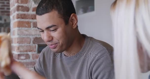 Grupo multiétnico de amigos as pessoas gostam de almoçar ou jantar juntos comendo pizza interior na moderna casa industrial. Homem negro a rir. 4k tiro de vídeo portátil — Vídeo de Stock