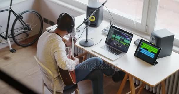 Черный человек творческий музыкант в домашней студии работает, играя, пение и запись гитары с ноутбука планшета и микрофона в помещении современного промышленного дома. Съемка 4k карманного видео сверху — стоковое видео