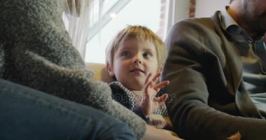 modern aile küçük kız kedi ve anne baba süre oynamaya kanepede kapalı modern endüstriyel ev içinde defter ile çalışır. Beyaz. 4 k el ağır çekim video çekim
