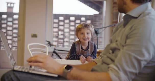 Modern familj lilla flickan springa och spela hemma med pappa arbetar med notebook. inomhus i moderna industriella hus. kaukasiska. 4 k handhållna slow motion video skott — Stockvideo