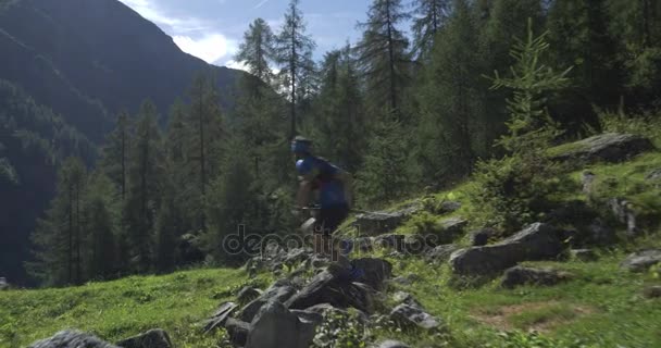 Caucasian trail runner running in mountain through woods, villages. 4k gimbal wide back video shot — Stock Video