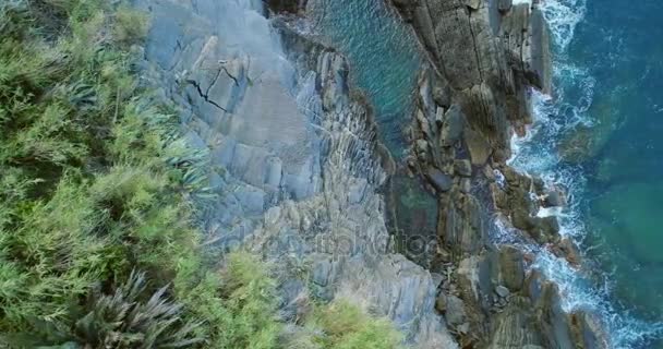 Vista aérea aérea sobre o mar Mediterrâneo mar ondas atingindo e bater na costa rochosa praia costa, perto de Cinque terre National Park, Ligúria, Itália. Tempo ensolarado. 4k vista superior drone lado vídeo tiro — Vídeo de Stock