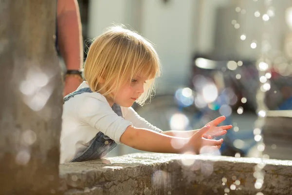 Jeune bébé caucasien blonde fille lavage des mains à la fontaine de la ville — Photo