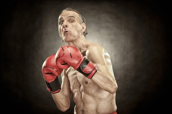Homem boxeador sênior com luvas vermelhas retrato velho no fundo texturizado — Fotografia de Stock