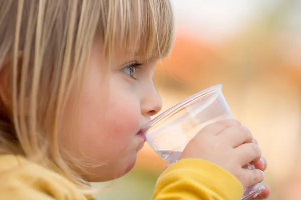 Baby blonde girl outdoor drinking water — Stock Photo, Image