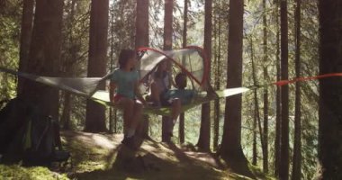 üç kişi yakın göl güneşli ormandaki çadır kamp asılı konuşuyor. Arkadaşlar yaz macera yolculuğun dağ doğa açık havada grup. Alps,Dolomites,Italy.4k ağır çekim 60 p keşfetmek seyahat