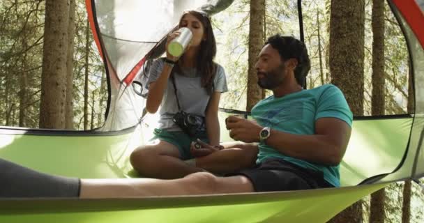 Deux hommes femme gens boire sur tente suspendue camping dans la forêt ensoleillée.Groupe d'amis voyage aventure d'été en montagne nature extérieur.Voyage explorer les Alpes, Dolomites, Italie.4k ralenti 60p — Video