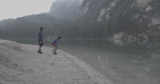 Ζευγάρι παίζει Πέτα πετρώματα σε Λίμνη Braies — Αρχείο Βίντεο