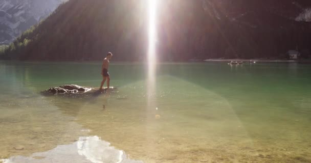 男は実行していると、野生の日当たりの良い明確な湖に飛び込む — ストック動画