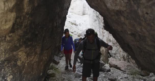 登山道の岩が多い峡谷路に沿って歩いている友人 — ストック動画