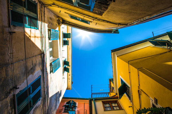 Look up view of famous travel landmark destination Riomaggiore colorful houses along street,small mediterranean old sea town,Cinque terre National Park,Liguria, Italy.Summer sunny morning with clouds.