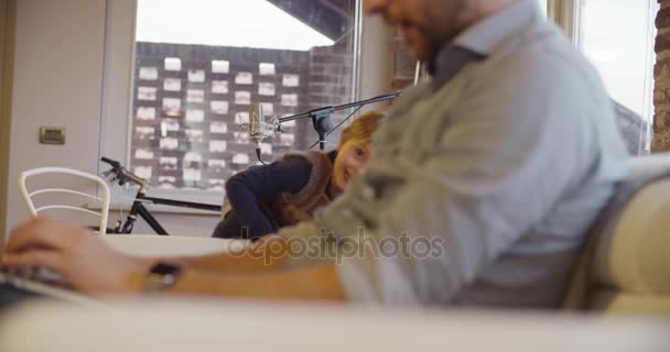 Petite fille de la famille moderne courir et jouer à la maison avec papa travaillant avec ordinateur portable. intérieur dans la maison industrielle moderne. caucasien. Prise de vue vidéo au ralenti portable 4k — Video