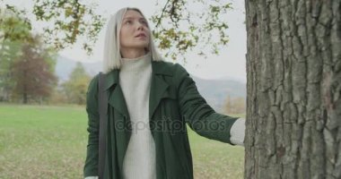 Ağaç dokunmadan sonbahar doğru yürüme Beyaz sarışın kadın slomo. Önünde gimbal takip. Hikaye anlatımı çok genç yetişkin insanlar sonbahar forest.4k yavaş çekimde video yalnız