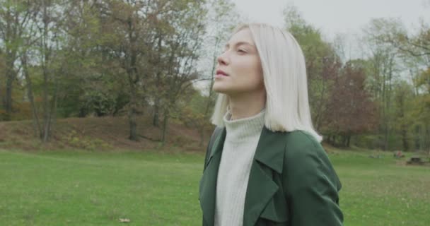 Medium skott. Kaukasiska blond kvinna slomo gående mot faller skogen. Följande sida gimbal. Berättande riktigt unga vuxna människor enbart i höst forest.4k slow motion video — Stockvideo