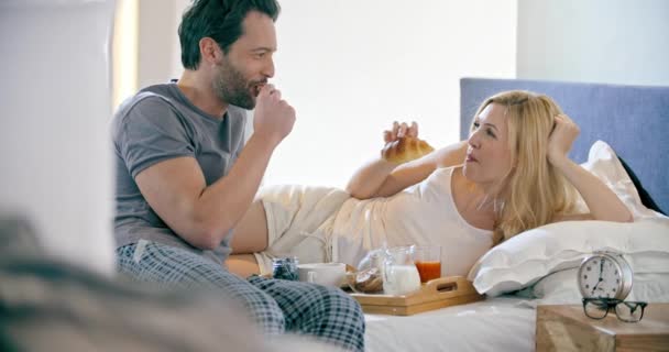 Bellissimo uomo e donna che fanno colazione con brioches nel letto.Coppia innamorata mattina svegliarsi a casa in camera da letto. Ragazza caucasica e fidanzato persone sdraiate sul letto. Bellissimi ictus. 4k video — Video Stock