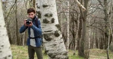 ormanda bakarak adam ve kamera fotoğraf çekmek. Aşağıdaki yan. Sonbahar season.4k videoda fotoğraf Shoot kırsal alanda yürüyüş bin yıllık yolcu backpacker yetişkin erkek fotoğrafçı gerçek kişiler