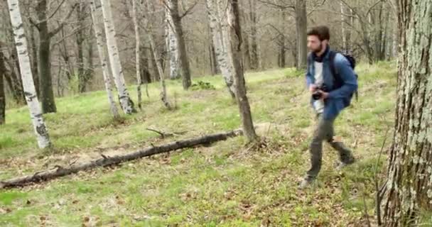 Fotoğraflar için seyir ormanda hiking adam. Aşağıdaki yan. Sonbahar mevsiminde fotoğraf Shoot kırsal alanda yürüyüş gerçek insanlar bin yıllık yolcu backpacker yetişkin erkek fotoğrafçı. 4k video — Stok video