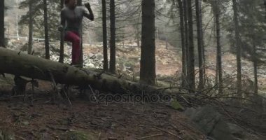 Sporcu kız günlük orman ormanda atlama. Aşağıdaki yan. Gerçek insanlar kadın atlet spor sonbahar ya da kış vahşi dağ açık havada doğa, kötü sisli weather.4k 60 p ağır çekim video eğitim