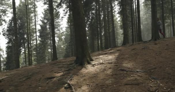 Atleet meisje loopt door bos bossen. Volgende kant. Echte mensen vrouw runner sport opleiding in de herfst of winter in wilde berg buiten natuur, slechte mistige weather.4k 60p slow motion video — Stockvideo