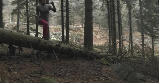 운동선수 여자는 숲 숲에 로그를 점프입니다. 다음 측면입니다. 진짜 사람 여자 러너 스포츠 자연, 나쁜 안개 weather.4k 60 p 슬로우 모션 비디오 야생 산 야외에서을 또는 겨울 훈련 — 비디오